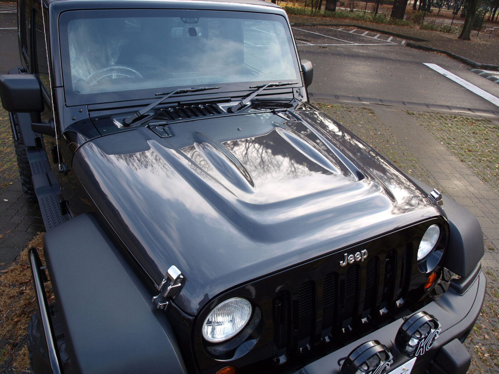 JK WRANGLER UNLIMITED RINEI オリジナルのFRP製カーボンボンネット。走行負圧でエンジンルームの熱気を抜き、ラジエターの冷却効率をアップさせる。